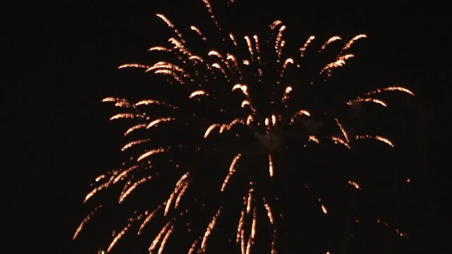 Bright golden fireworks exploding in the midnight sky during a festive celebration. Amazing sparkling effect for New Year's Eve, party promotions, and emotional abstract backgrounds.