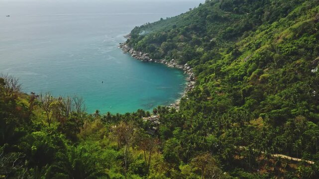 Secluded bay with turquoise water along the lush green tropical jungle coastline, showcasing the natural beauty of Phuket, Thailand for travel and tourism concepts. Aerial view drone flight panorama