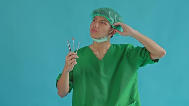 Dentist in scrubs holding tools and thinking deeply