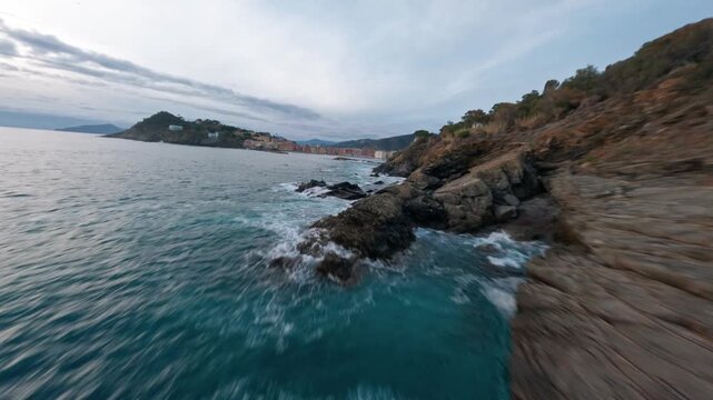 FPV Drone Shot Flying Low Along Rocky Coastline with Waves Crashing in Liguria Italy