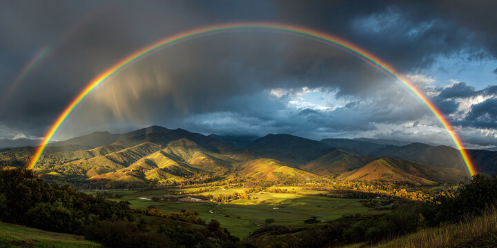 Rainbow Arc Over Mountain Valley with Dark Storm Clouds
