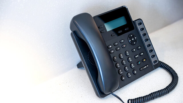 IP phone on the table in hotel room. Black landline telephone for communication support, call center and customer service help desk