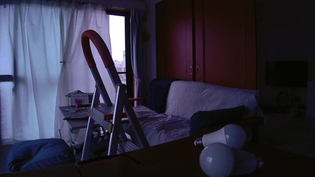 Replacing a light bulb in a quiet home with a gentle breeze, everyday maintenance scene with signs of daily life for lifestyle and home care use