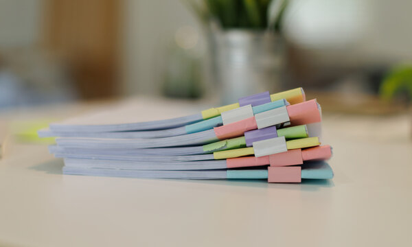 Stack of document files organized with colorful pastel binder clips, representing efficient paperwork management, office organization, and administrative tasks