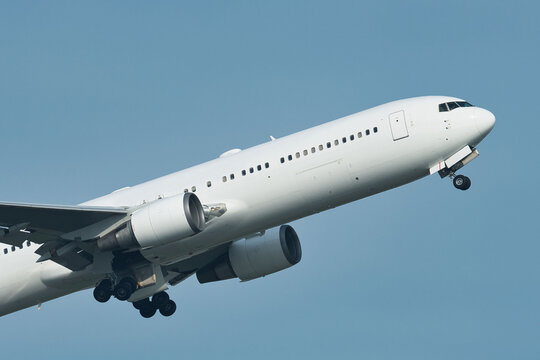 White passenger plane taking off under clear blue sky