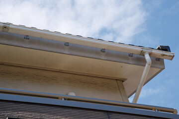 青空の背景に戸建て住宅の軒先と軒天などが汚れが目立っている状態 © hikari_stock