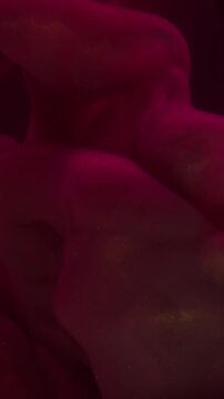 Vertical video. Red vapor. Ink background. Defocused vibrant color water glass swirling mist spreading on acrylic dark black creative abstraction.