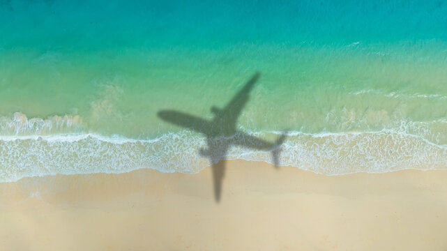 Aerial view of shadow passenger plane silhouette and sandy beach blue sea with waves at sea beach summer vacation sea travel concept	
