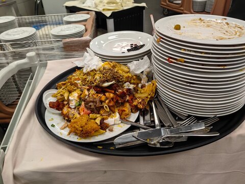 Piles of dirty dishes and leftovers on the trolli table in the kitchen restaurant area.