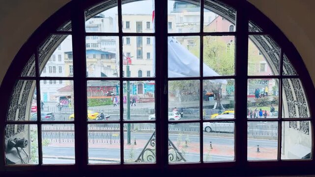 Scenic city life view with yellow taxis and people walking look through a large vintage arched wooden window frame with decorative ornaments from inside historic room.
