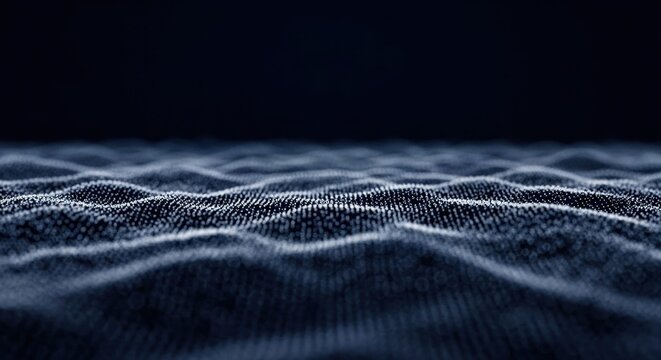 Abstract digital terrain composed of glowing blue and white particles forming undulating wave patterns on a dark navy background with shallow depth of field and bokeh effect.