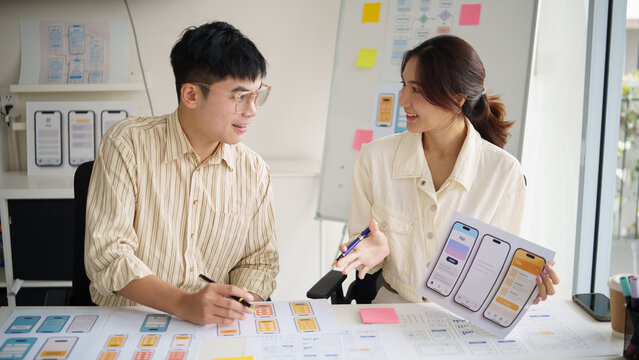 UX design team discussing mobile app wireframes during a creative planning meeting in a modern office.