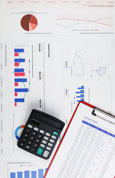 Vertical top view of financial report with charts, graphs, calculator, and clipboard on office desk. Business accounting data dashboard, tax budget planning, and investment analysis concept.