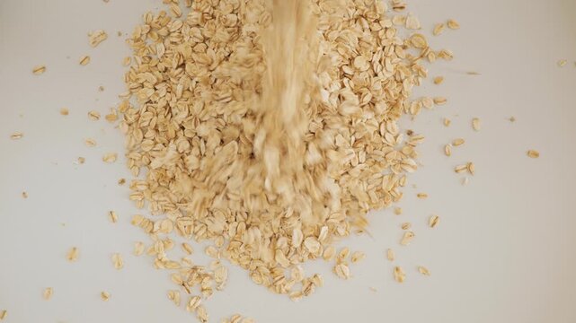 Raw rolled oats falling on an isolated white background