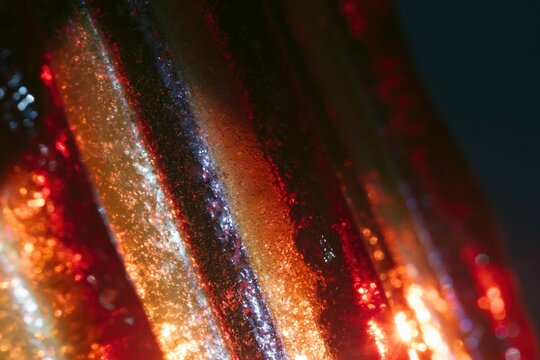 Ribbed glass surface with glowing amber and violet highlights creates a vivid, grainy abstract texture for modern architectural background design