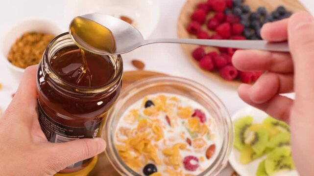 Person Scooping Fresh Honey From Jar for Healthy Breakfast Bowl