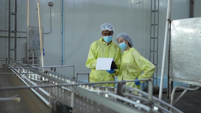 Sterile environment production team performing quality assurance on canned goods, Food safety professionals examining production line in a modern manufacturing plant