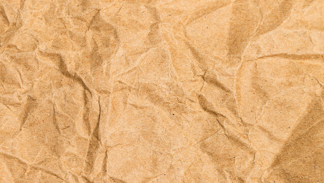 Crumpled brown kraft paper texture background. Full frame close up of wrinkled recycled paper sheet. Concept for eco friendly package material, abstract background and vintage design
