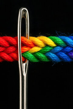 Close up of a sewing needle with colorful rainbow braided rope on a dark background. Craft, tailoring and textile concept. Generative AI illustration.