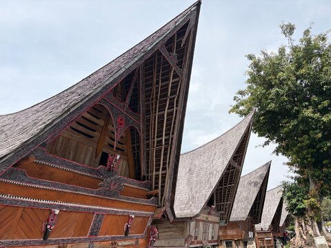 Traditional Batak Toba traditional house (Rumah Bolon) with its iconic boat-shaped roof and intricate Gorga carvings in Samosir Island, Lake Toba, Indonesia