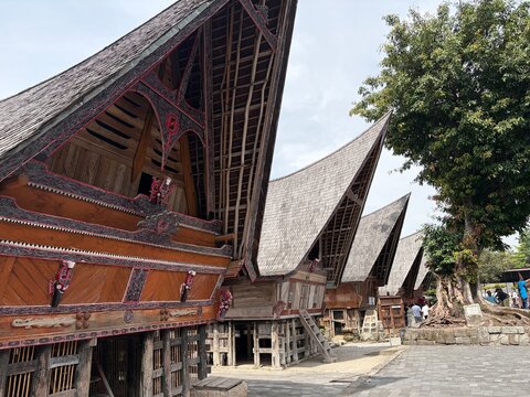 Traditional Batak Toba traditional house (Rumah Bolon) with its iconic boat-shaped roof and intricate Gorga carvings in Samosir Island, Lake Toba, Indonesia