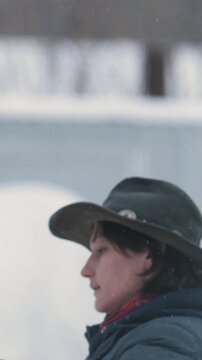 Woman is trying leads stubborn horse to walking in snowy paddock during snowfall