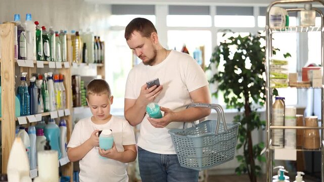Dad and son scan barcode on packaging of shampoo, looking for information about product on website. Boy watches actions of dad, learns to scan QR code using phone camera