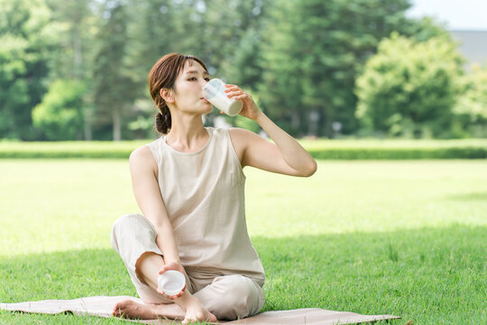 A woman drinking protein while doing yoga in the forest