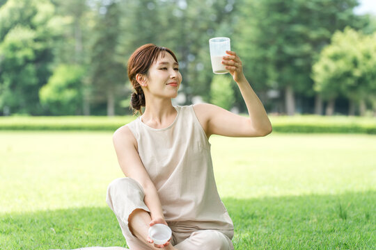 A woman drinking protein while doing yoga in the forest