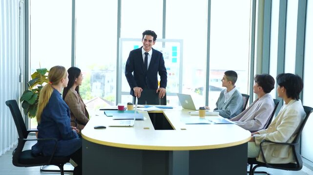 Male manager introduces team representative to continue presentation during corporate meeting.  