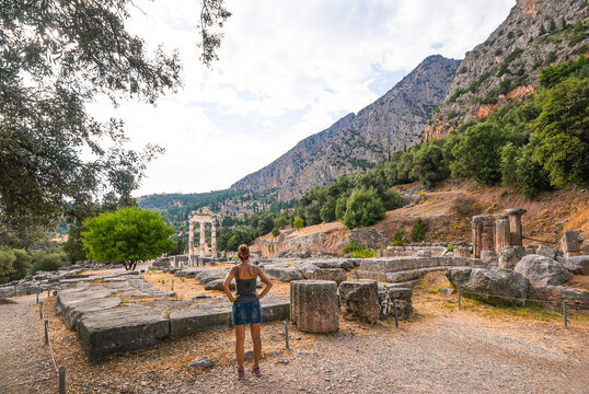 Woman exploring ancient Greek ruins at Delphi sanctuary