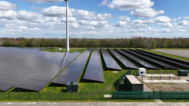 Aerial drone view of a battery energy storage system at a solar and wind park, showing renewable energy infrastructure, grid balancing, energy storage, net congestion prevention, load balancing, and t