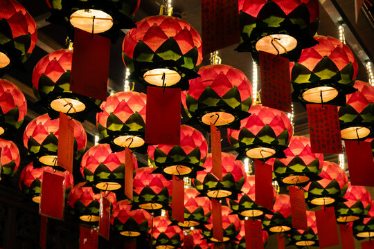 Rows of glowing red lotus-shaped paper lanterns with personal blessing tags hanging from the ceiling of the Hung Shing Temple in Wan Chai shortly after Chinese New Year 2026