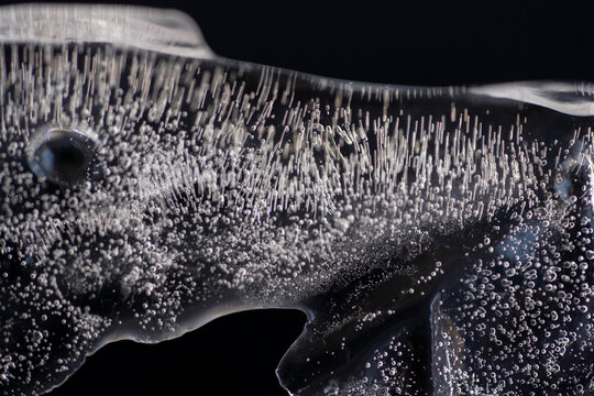 acercamiento a bloque de hielo con burbujas dando formas abstractas con fondo negro