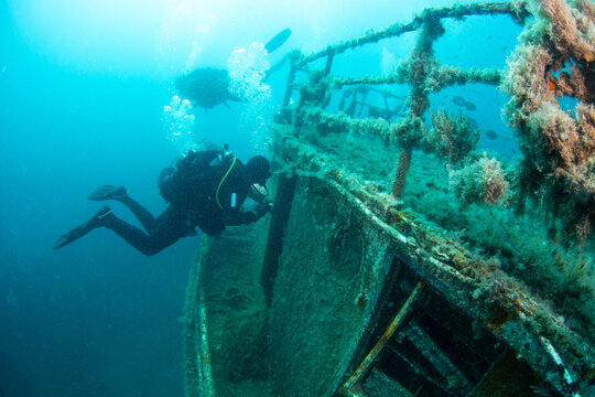 Diving near a sunken ship wreck in clear water with fish swimming around in a tropical location