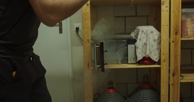 smoke escaping from a microwave oven during a household fire incident. Suitable for kitchen accidents, appliance malfunction, fire hazards, smoke damage, home safety, and emergency concepts.