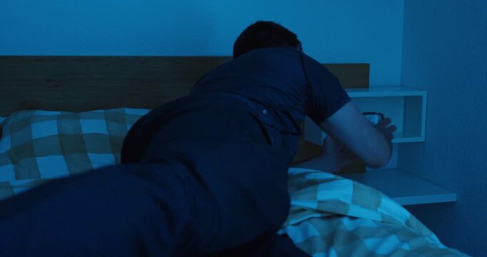 man sleeping, noticing the time on a bedside clock, realizing he overslept, and immediately getting up. Suitable for morning stress, lateness, alarm concepts, daily routines, work pressure