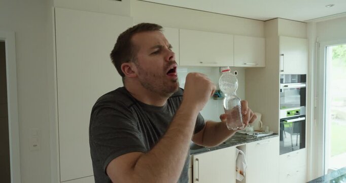 choking and coughing while drinking water from a plastic bottle in a kitchen environment. Suitable for swallowing problems, aspiration risk, healthcare, first aid, dehydration, and everyday accident