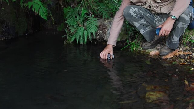 A Visitor Collects Water From a Calm Natural Spring Surrounded by Lush Greenery in Ca&ntilde;&oacute;n de la Garita, Sierra de P&eacute;njamo, Guanajuato, Mexico - Medium Shot