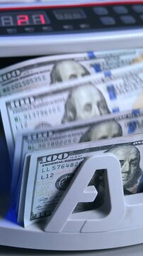Money counter machine counting hundred dollar bills in motion showing financial transaction and business operation.