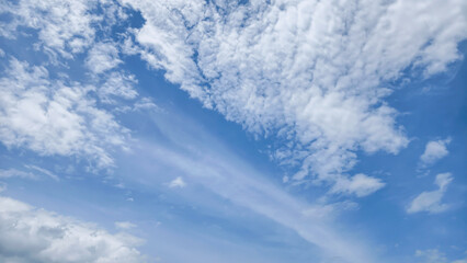 Fototapeta premium Wispy White Clouds Drifting Across A Clear Bright Blue Sky On A Beautiful Sunny Summer Day