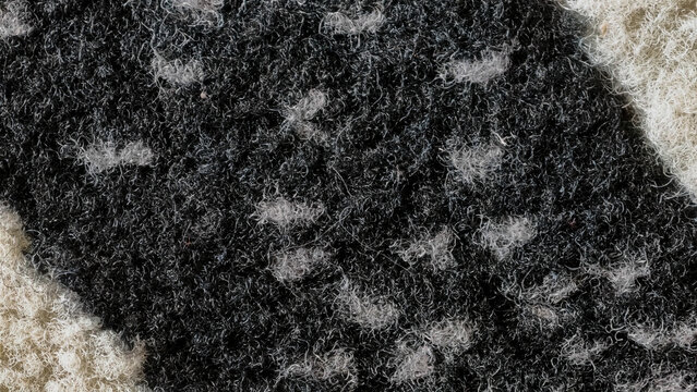 Close-up texture of a dark grey and off-white woven fabric with a speckled pattern, showcasing intricate textile details