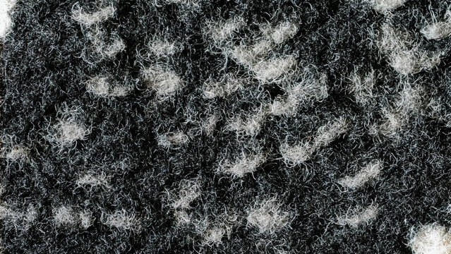 Macro view of the black and white speckled texture of the doormat showing its grain pattern.