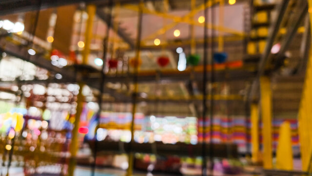 Defocused background of kids indoor play area featuring rope course obstacles and climbing frames in amusement center