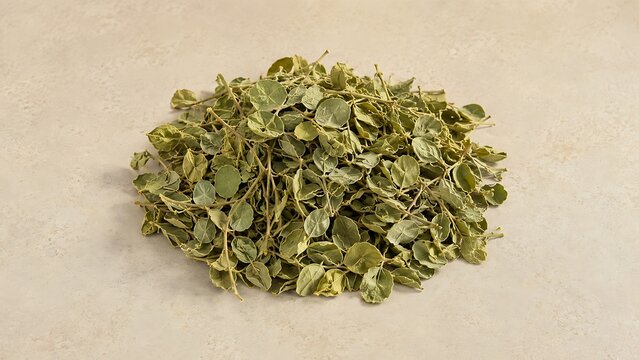 Pile of dried moringa oleifera leaves on a light beige background