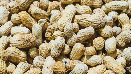 Fototapeta premium A large pile of roasted peanuts in their textured shells, providing a detailed overhead view of organic snacks