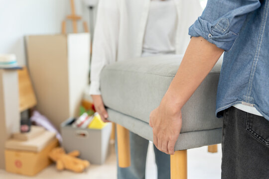 Moving house, relocation. Couple help set sofa and move furniture for new apartment, inside the room was a cardboard box contain personal belongings. move in the new apartment or condominium