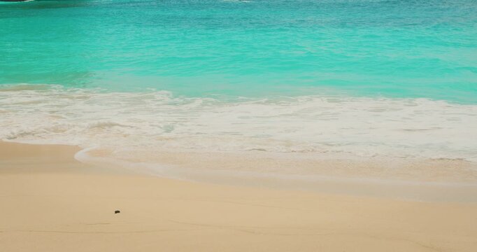 Crystal clear turquoise ocean water washes onto sandy shore in Nusa Penida Bali