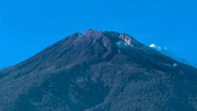Active volcanic mountain peak with rugged terrain under clear blue sky