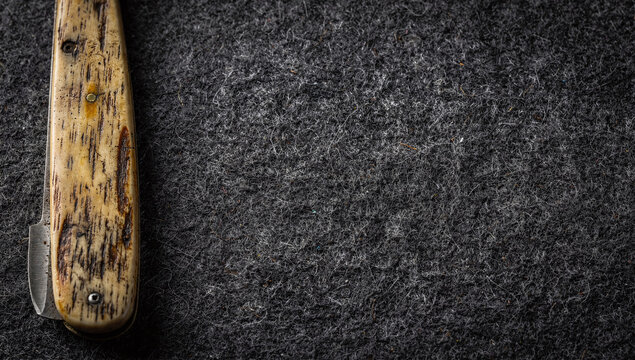 Close up of vintage folding pocket knife handle on dark grey felt fabric background